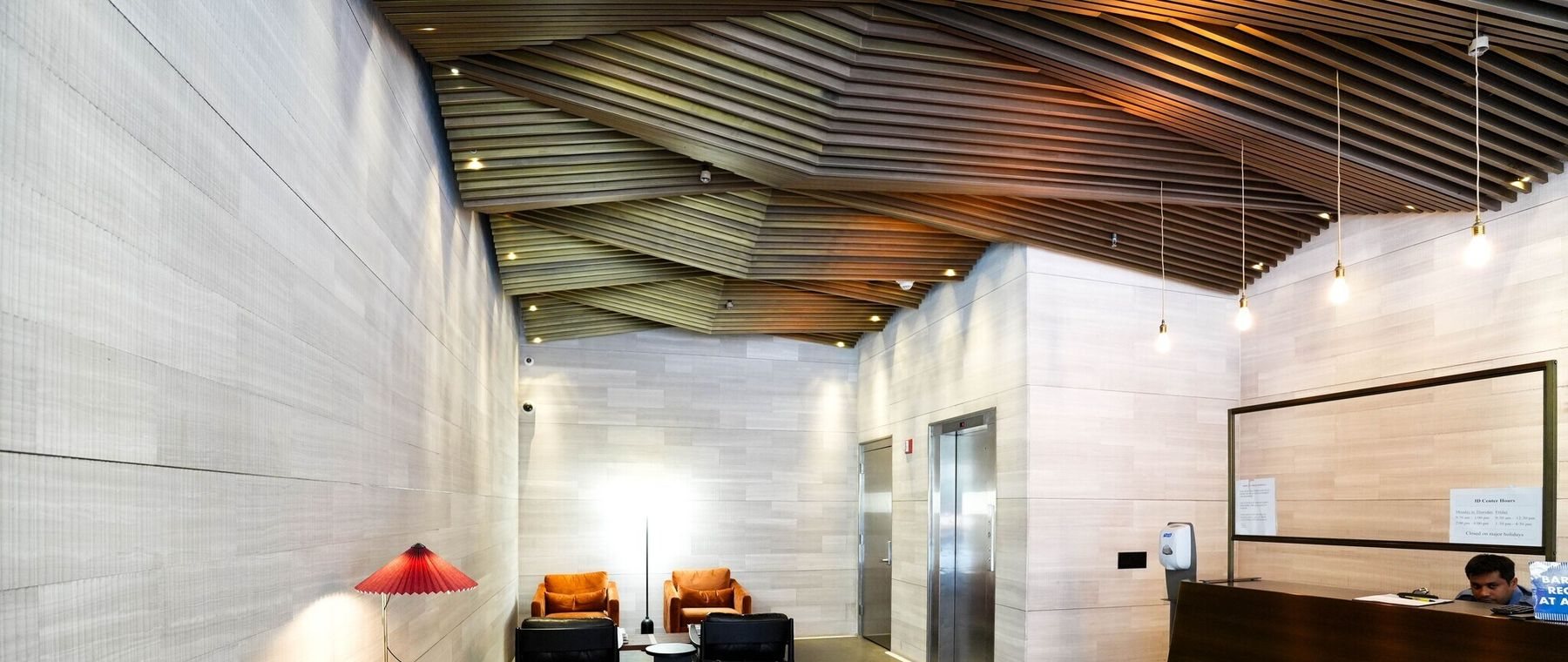 The renovated lobby ceiling, folded planes of wood slats over stone walls